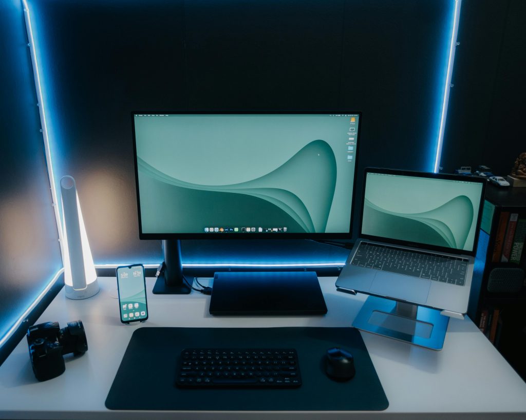 A sleek and modern desk setup featuring a monitor, laptop, and ambient lighting, perfect for productivity.