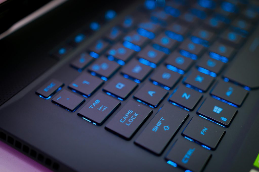 Close-up of an illuminated mechanical keyboard with blue backlit keys, perfect for tech enthusiasts.