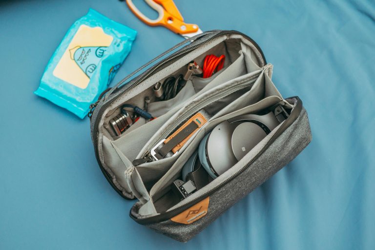 A top view of an organized travel tech bag filled with headphones, cables, and wipes.