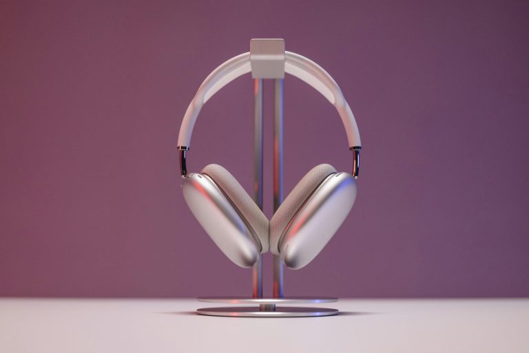 Stylish over-ear headphones displayed on a stand against a pink backdrop.