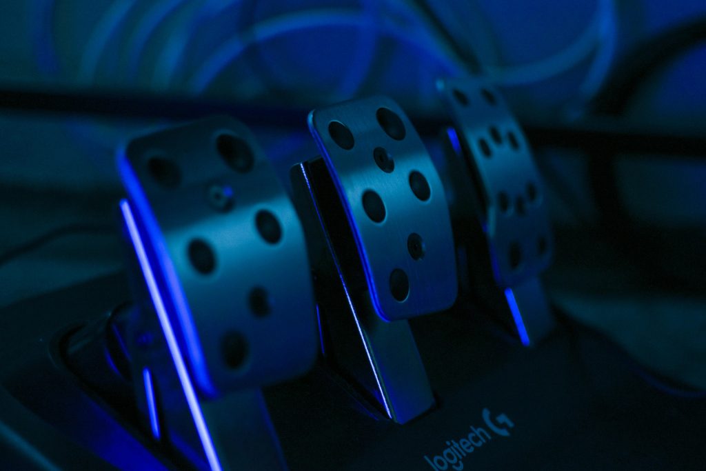 Detailed shot of gaming pedals illuminated by blue light, perfect for racing simulation setups.